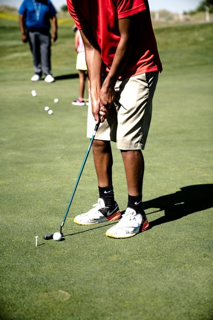 A golfer practicing a putt during a leisure game on a sunny day at the course.